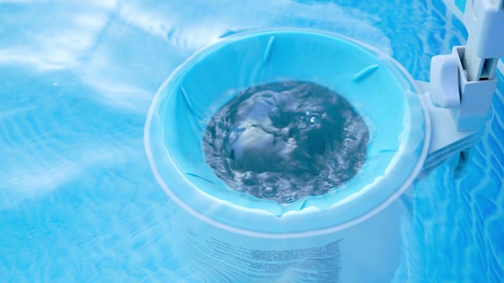 designer pool covers A blue bucket filled with water in a swimming pool covered with pool covers.