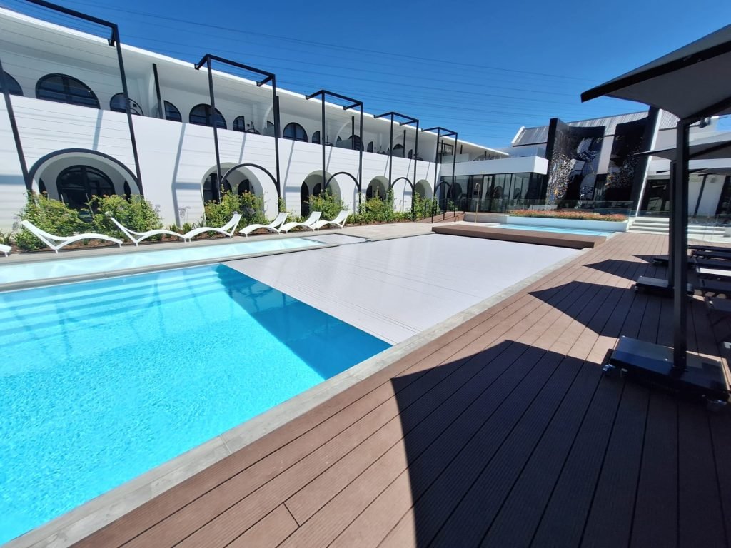 designer pool covers A swimming pool with lounge chairs and a wooden deck. If you're wondering how to keep cats off your pool cover, this serene oasis offers a solution. With comfortable lounge chairs and a beautiful