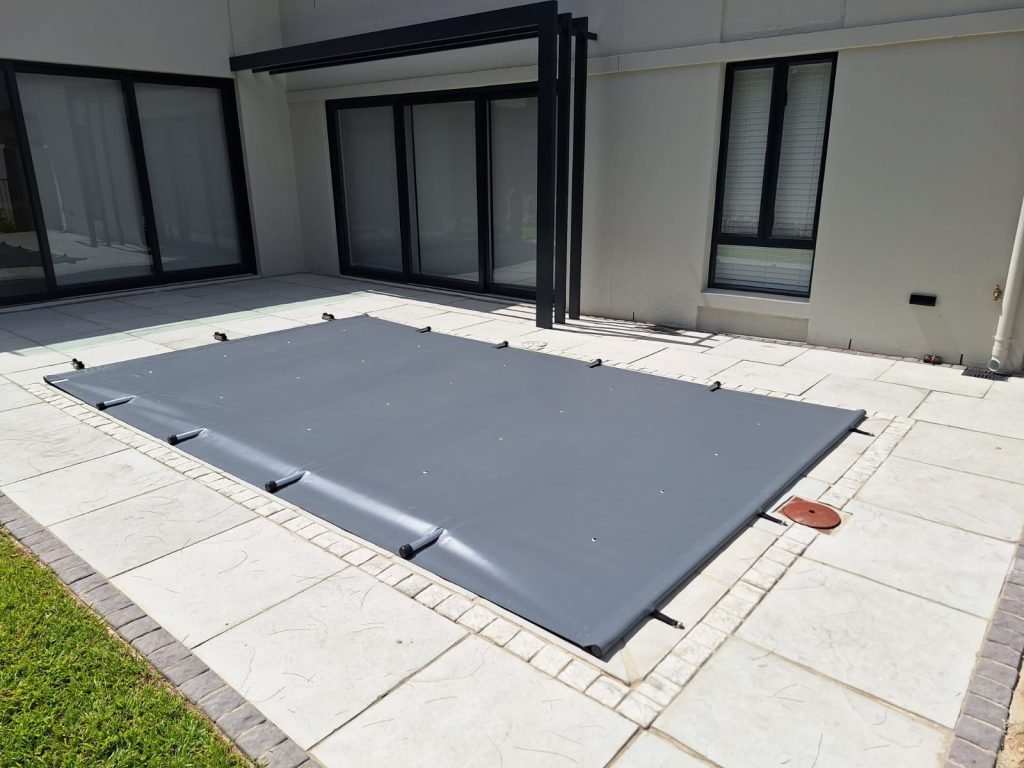 designer pool covers A grey pool cover on the patio of a house, providing an effective solution to keep cats off.