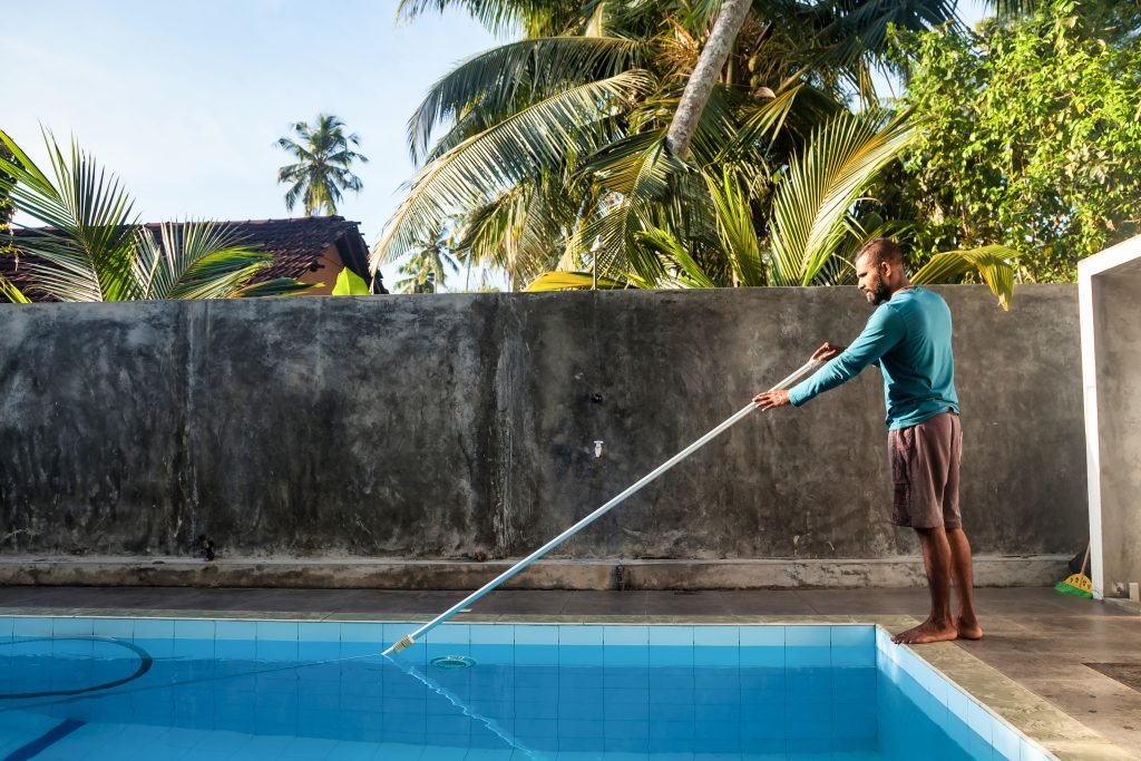 designer pool covers A man cleaning a swimming pool in sri lanka with pool covers.